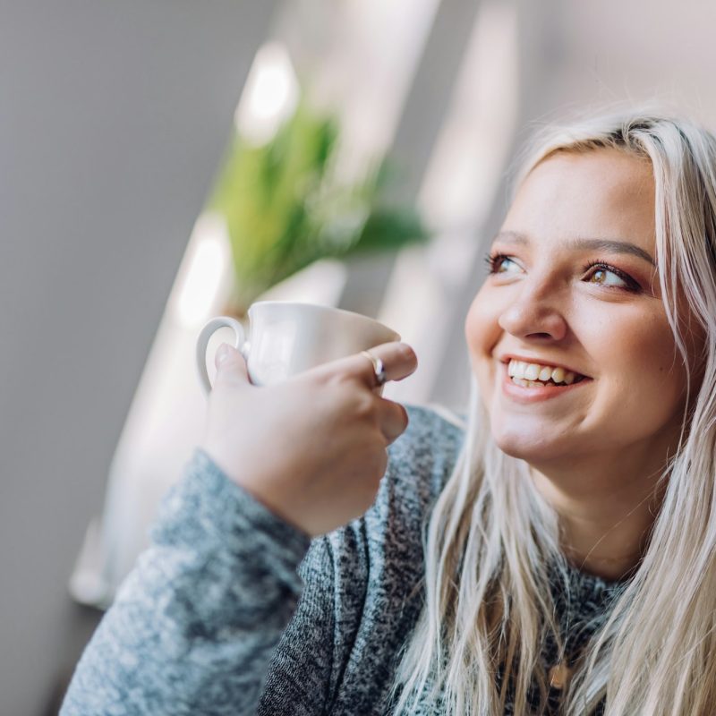 Positive woman holding cup in office